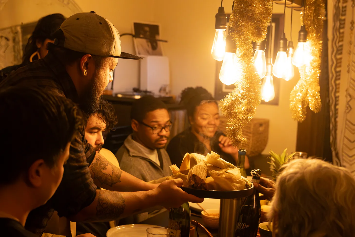 Jeremy serving a plate of tamales to a table full of smiling people